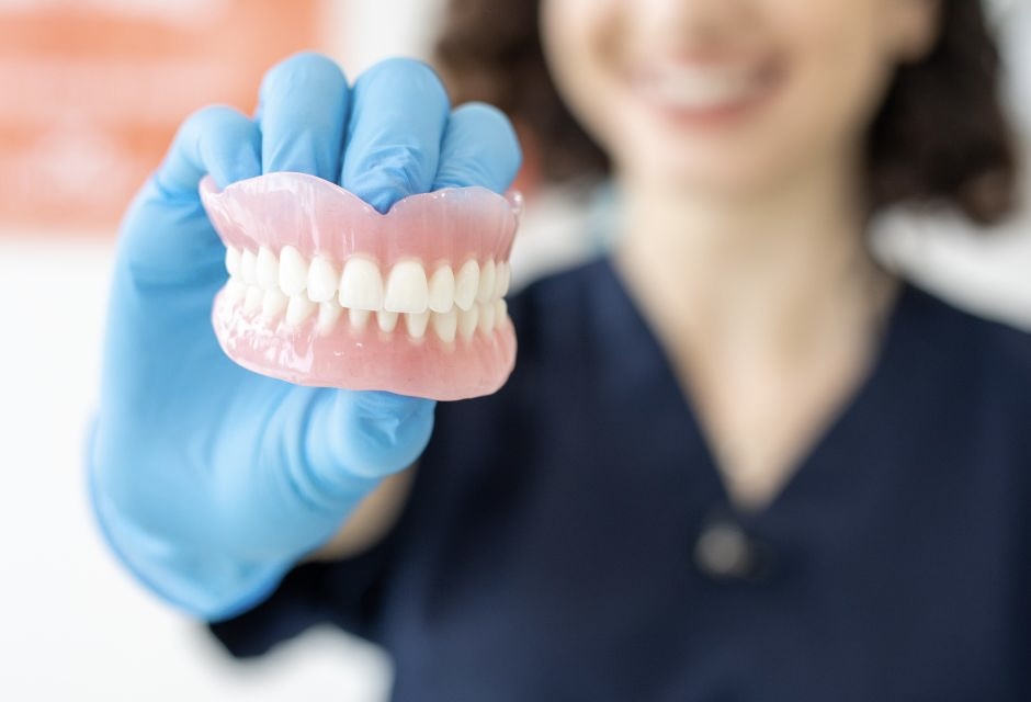 lekarz dentysta trzyma w ręku protezy zębowe