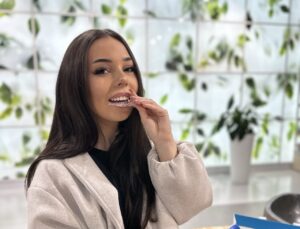 pacjentka zakłada przezroczystą nakładkę Invisalign podczas leczenia ortodontycznego