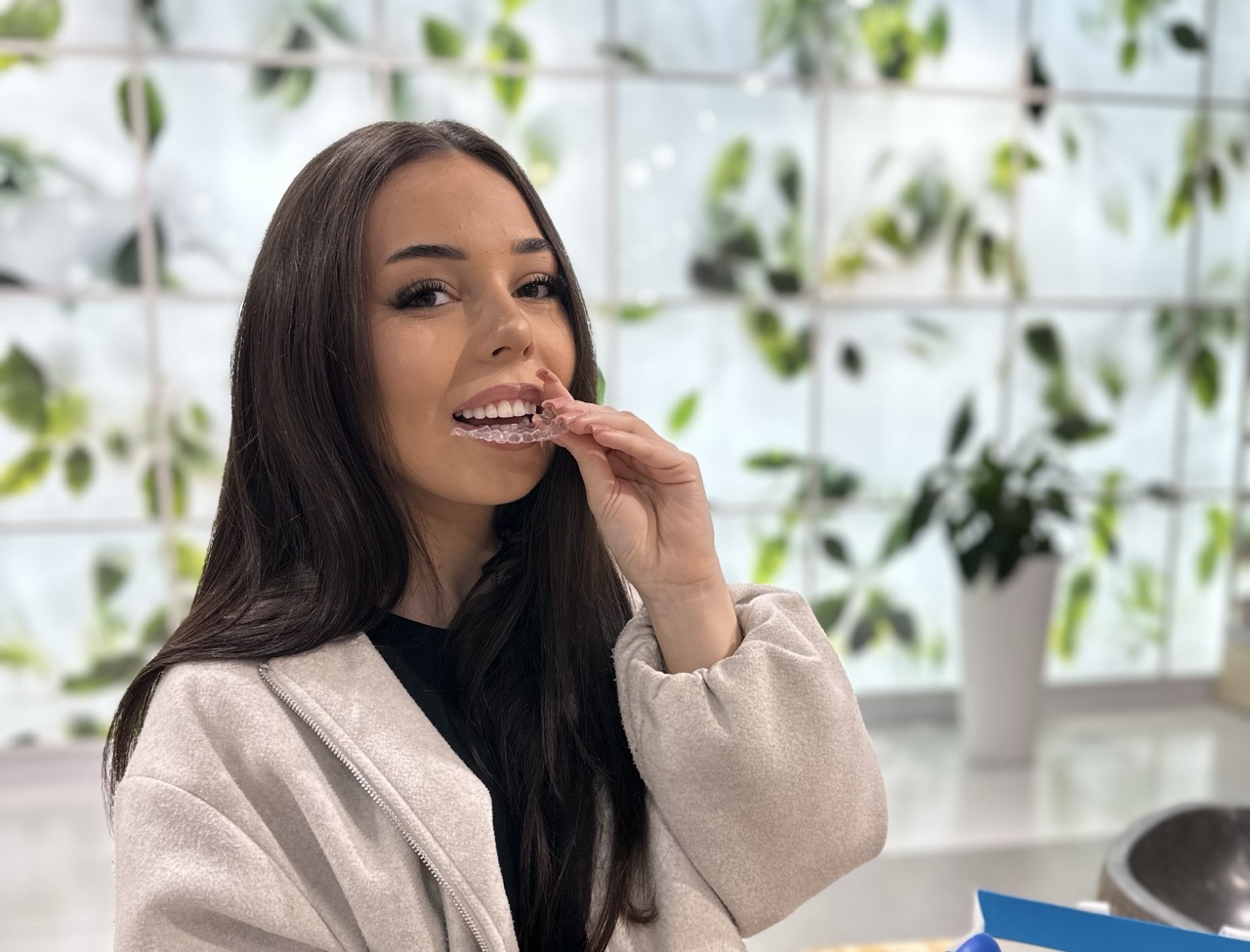 pacjentka zakłada przezroczystą nakładkę Invisalign podczas leczenia ortodontycznego