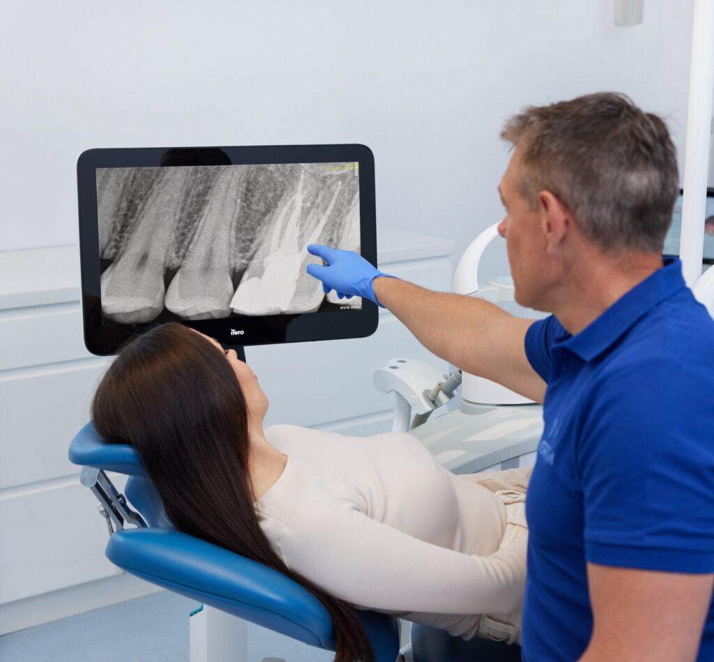 Dentysta omawia leczenie kanałowe na podstawie zdjęcia RTG z pacjentem