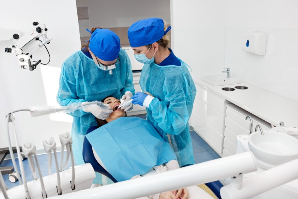 Zabieg usuwania zęba mądrości wykonywany przez dentystę w znieczuleniu